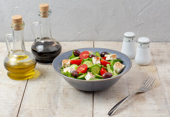 Fresh vegan salad from green leaves mix, vegetables, cheese, spices, olive oil and balsamic. Spring salad, healthy concept.  Wooden background