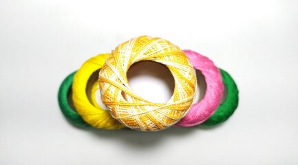 Fototapeta premium Bunch of double shaded Multicolor mercerized knitting cotton crochet yarn small thread ball or spool stacked together on white table background with copy space. Stitch, needlework, embroidery concept.
