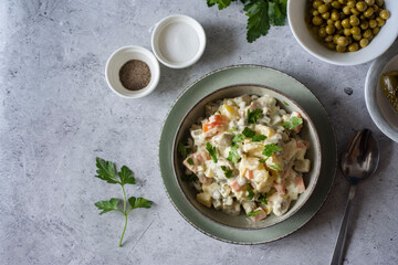 Breakfast for the family: salad with peas, vegetables and mayonnaise in a beautiful plate on a gray background. Vegetable salad for lunch. A festive dish.