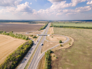 Aerial view of road interchange or highway intersection with traffic speeding on the road