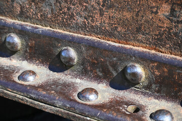 A fragment of an old rusty metal I-beam with rivets. Metal detail riveted with rivets close-up.