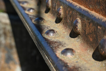 A fragment of an old rusty metal I-beam with rivets. Metal detail riveted with rivets close-up.