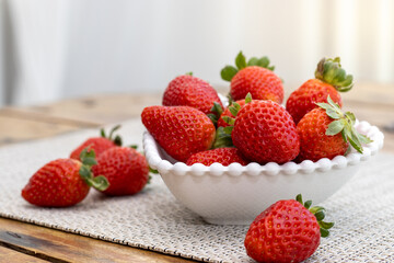 Delicious ripe fresh strawberries in a white bowl on a wooden table background