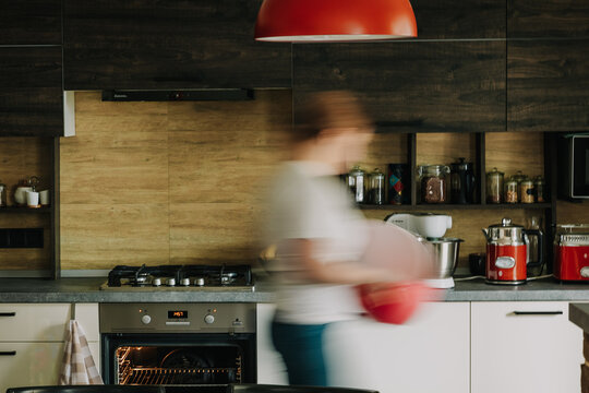 the photo is stylishly designed for the interior of the kitchen with a woman walking along it in the prepared home