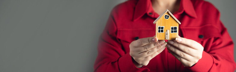Hands of woman holding model house.