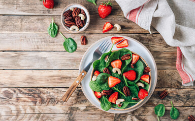 Fresh strawberry salad with spinach leaves and nuts.