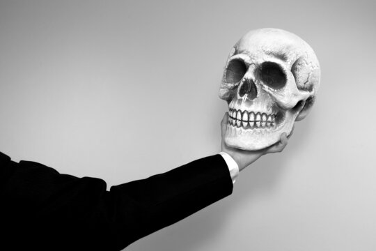 A hand holding a human skull. Black and white grunge background.