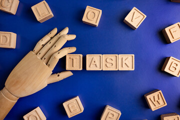 TASK the word on wooden cubes with wooden hand on blue background . Business and finance concept