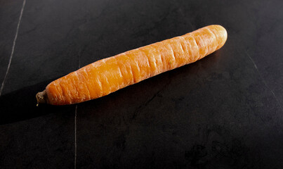big carrot on the table, on a black background