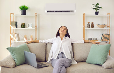 Woman enjoying modern AC system in her home. Happy relaxed middle aged lady breathing in fresh air...