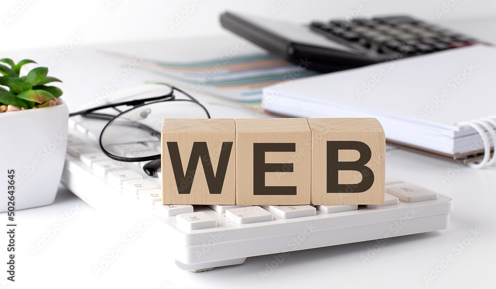 Poster web s written on a wooden cube on keyboard with office tools