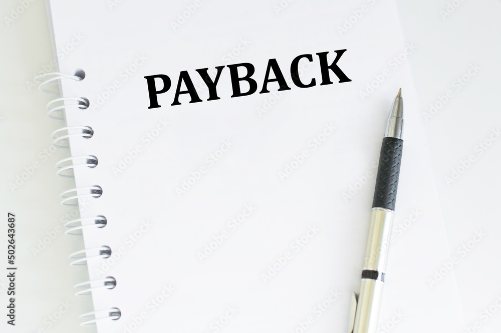 Poster payback text on a notepad on a table next to a pen, a business concept