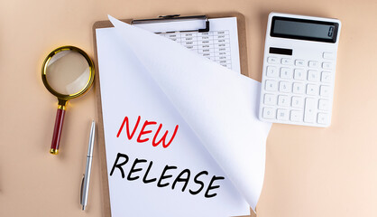 Clipboard with chart and text NEW RELEASE with magnifier ,calculator on beige background