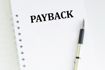 PAYBACK text on a notepad on a table next to a pen, a business concept