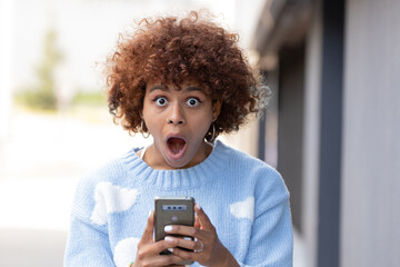 girl in the street with mobile phone and expression of surprise
