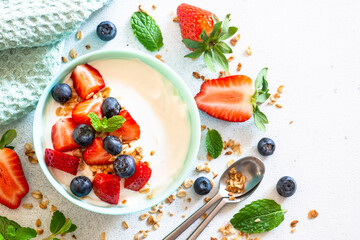 Greek Yogurt with granola and fresh berry mix at white stone table. Top view with copy space.