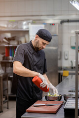 The chef marinates vegetables for grilling