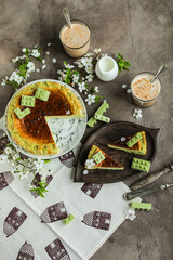 Cheesecake with matcha decorated with designer chocolate. Grilled San Sebastian cheesecake with green tea on a table with coffee and spring flowers.