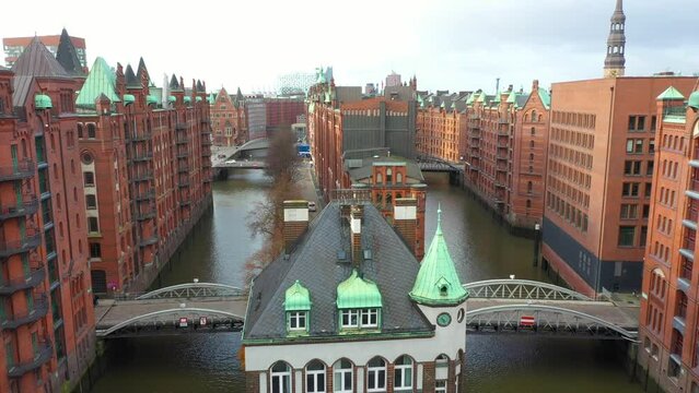 Old red-brick buildings in Speicherstadt along a canal with bridges. Flight through the Warehouse district, downtown in Hamburg, Germany. Aerial drone view. 4K 