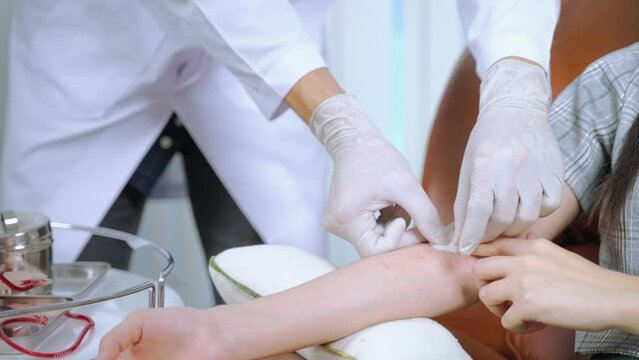 The doctor is using a cotton swab to stop the bleeding for the blood donor on the arm after the blood donation is complete.
