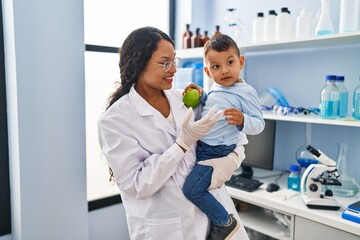 Obraz premium Mother and son wearing scientist uniform hugging each other at laboratory