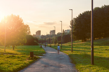 People walking through the city park on a sunny summer evening