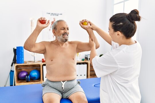 Physiotherapist and patient smiling confident having rehab session using power balls at clinic