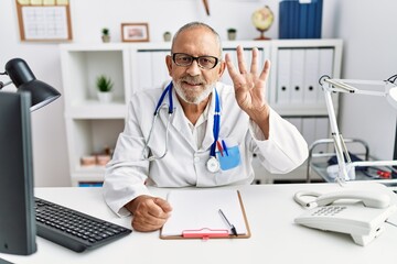 Obraz premium Mature doctor man at the clinic showing and pointing up with fingers number four while smiling confident and happy.