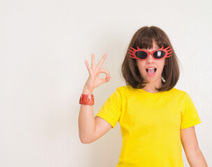 Comic, charming, positive, girl showing ok gesture. Crasy teen girl wearing party  glasses. Party time.