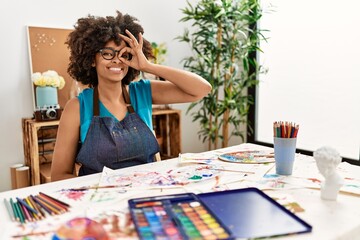 Beautiful african american woman with afro hair painting at art studio doing ok gesture with hand smiling, eye looking through fingers with happy face.
