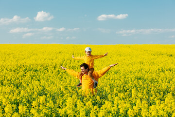 Father with a son in rapeseed field in spring time