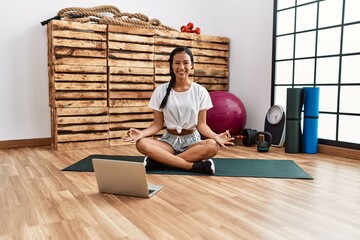 Young latin woman smiling confident having online yoga class at sport center