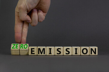 Zero emission symbol. Businessman turns wooden cubes and changes words Emission to Zero emission. Beautiful grey background. Business, ecological and zero emission concept. Copy space.