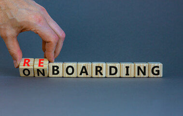 Onboarding or reboarding symbol. Businessman turns wooden cubes and changes words Onboarding to Reboarding. Beautiful grey table grey background. Business onboarding or reboarding concept. Copy space.