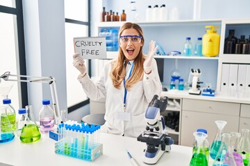 Young blonde scientist woman working on cruelty free laboratory celebrating victory with happy...
