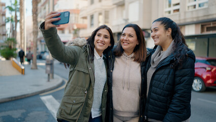 Mother and daugthers making selfie by the smartphone standing together at street