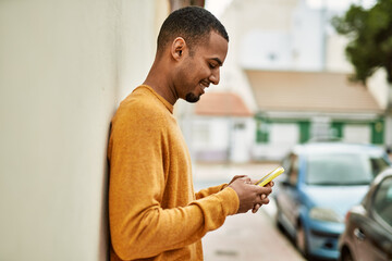 Young african american man smiling happy using smartphone at the city.