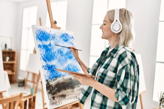 Young artist student girl smiling happy painting and listening music at art studio.