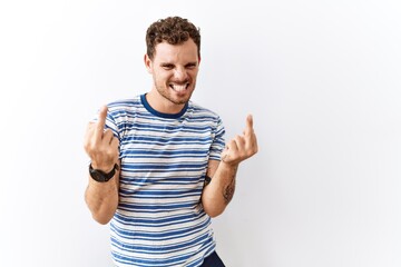 Handsome young man standing over isolated background showing middle finger doing fuck you bad expression, provocation and rude attitude. screaming excited