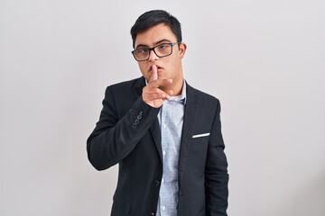 Young hispanic man with down syndrome wearing business style asking to be quiet with finger on lips. silence and secret concept.
