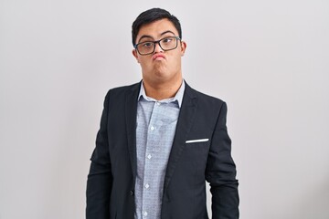 Young hispanic man with down syndrome wearing business style depressed and worry for distress,...