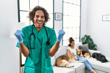 Young veterinarian man checking dogs at home screaming proud, celebrating victory and success very...
