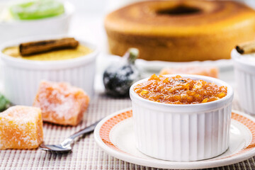pot with homemade pumpkin jam, typical Brazilian dessert at the June and July parties, in the background fuba cake and candied sweets