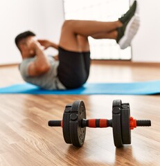 Fototapeta na wymiar Young hispanic man training abs exercise at sport center