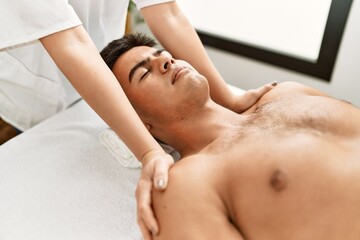 Fototapeta na wymiar Young hispanic man relaxed having shoulders massage at beauty center