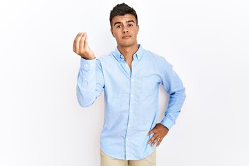 Fototapeta premium Young hispanic man wearing business shirt standing over isolated background doing italian gesture with hand and fingers confident expression