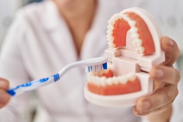 Middle age woman wearing dentist uniform teaching to wash tooth at clinic