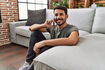 Young hispanic man smiling confident talking on the smartphone at home