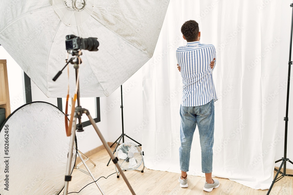 Poster Arab young man posing as model at photography studio hugging oneself happy and positive from backwards. self love and self care