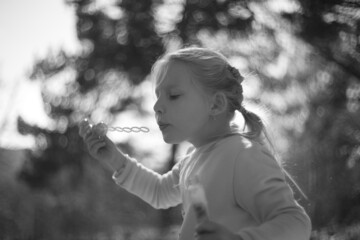 Young happy girl playing in nature with bubble blower